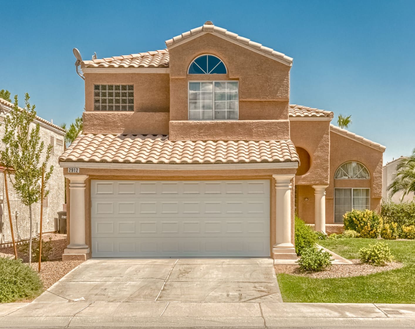 Cream stucco home with palm trees